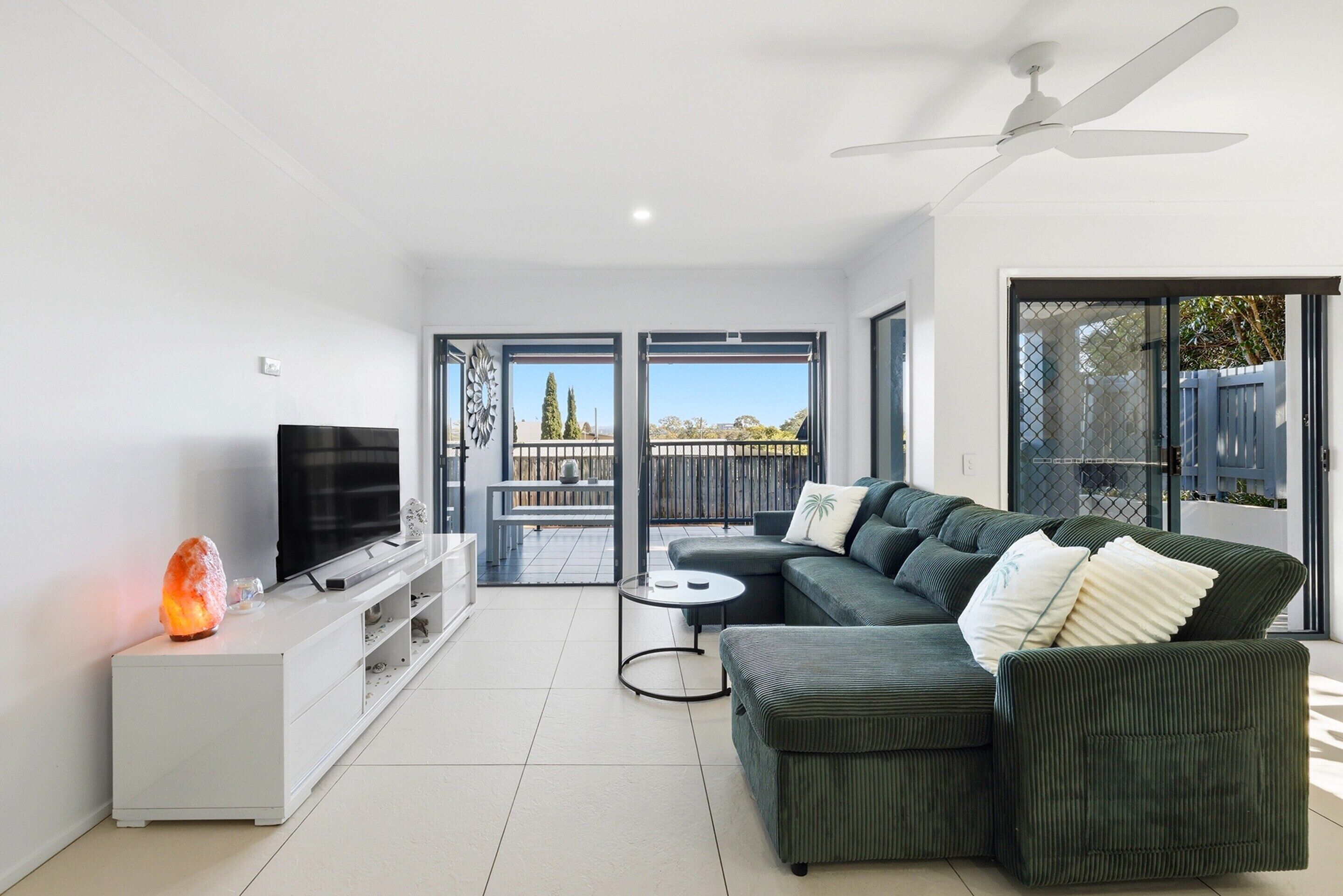 Una sala de estar moderna con un sofá modular, un televisor de pantalla plana, un calefactor y un balcón con vistas.