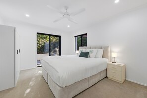 Une chambre à coucher avec un lit, une table de chevet, une lampe et un ventilateur de plafond.