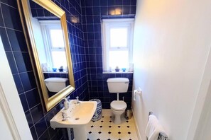 A bathroom with two toilets, a sink, and a mirror. - Apartment Sleeps 4 With Garden (Prestwick)