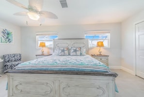 A bedroom with a bed, two bedside lamps, a ceiling fan, and a window. - Ga1970 3 Bedroom Home (Englewood)