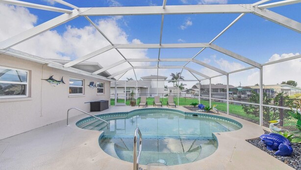 Une piscine couverte avec une structure en verre, un espace détente avec des fauteuils et une vue sur le paysage environnant.