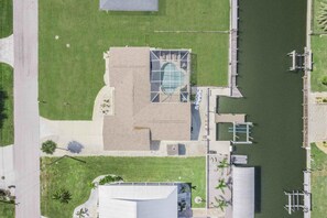 An aerial view of a building with a large glass facade, adjacent to a body of water, with a parking area and a grassy area. - Ga1970 3 Bedroom Home (Englewood)