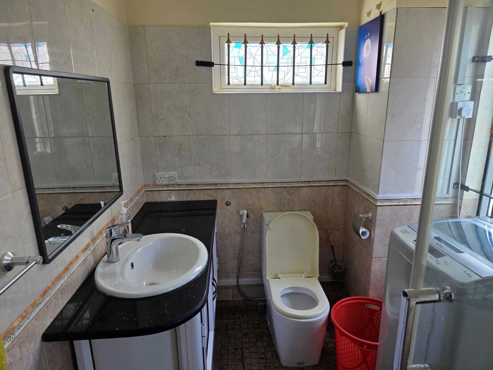 Ein Badezimmer mit Waschbecken, Toilette und einem Fenster mit Ziergitter.