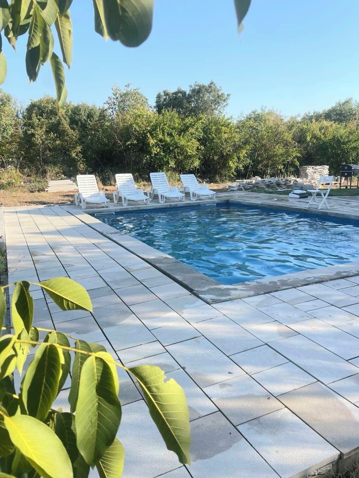 Une piscine entourée de chaises longues blanches et d’une terrasse carrelée.