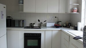 A kitchen with white cabinets, a microwave, a toaster, and a kettle. - Lemon Tree Cottage..a little piece of heaven (Johannesburg)