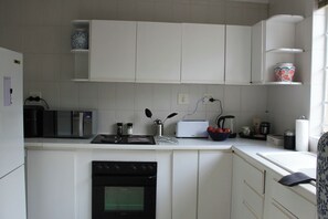 Eine Küche mit weißen Schränken, einer Mikrowelle, einem Toaster und einem Wasserkocher.