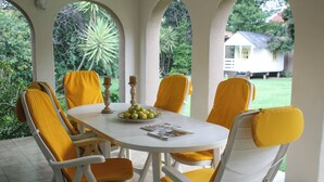 A white table with yellow chairs, a bowl of fruit, and a candle. - Lemon Tree Cottage..a little piece of heaven (Johannesburg)