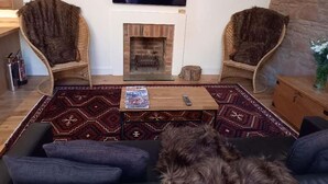 A living room with two armchairs, a sofa, a fireplace, a television, and a rug. - Holiday Cottage Sleeps 3 With Garden (Prestwick)
