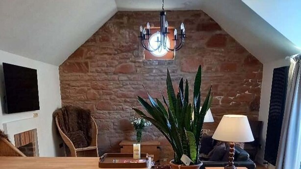 A cozy loft-style living space with a wooden bench, a potted plant, and a hanging light fixture. - Holiday Cottage Sleeps 3 With Garden (Prestwick)