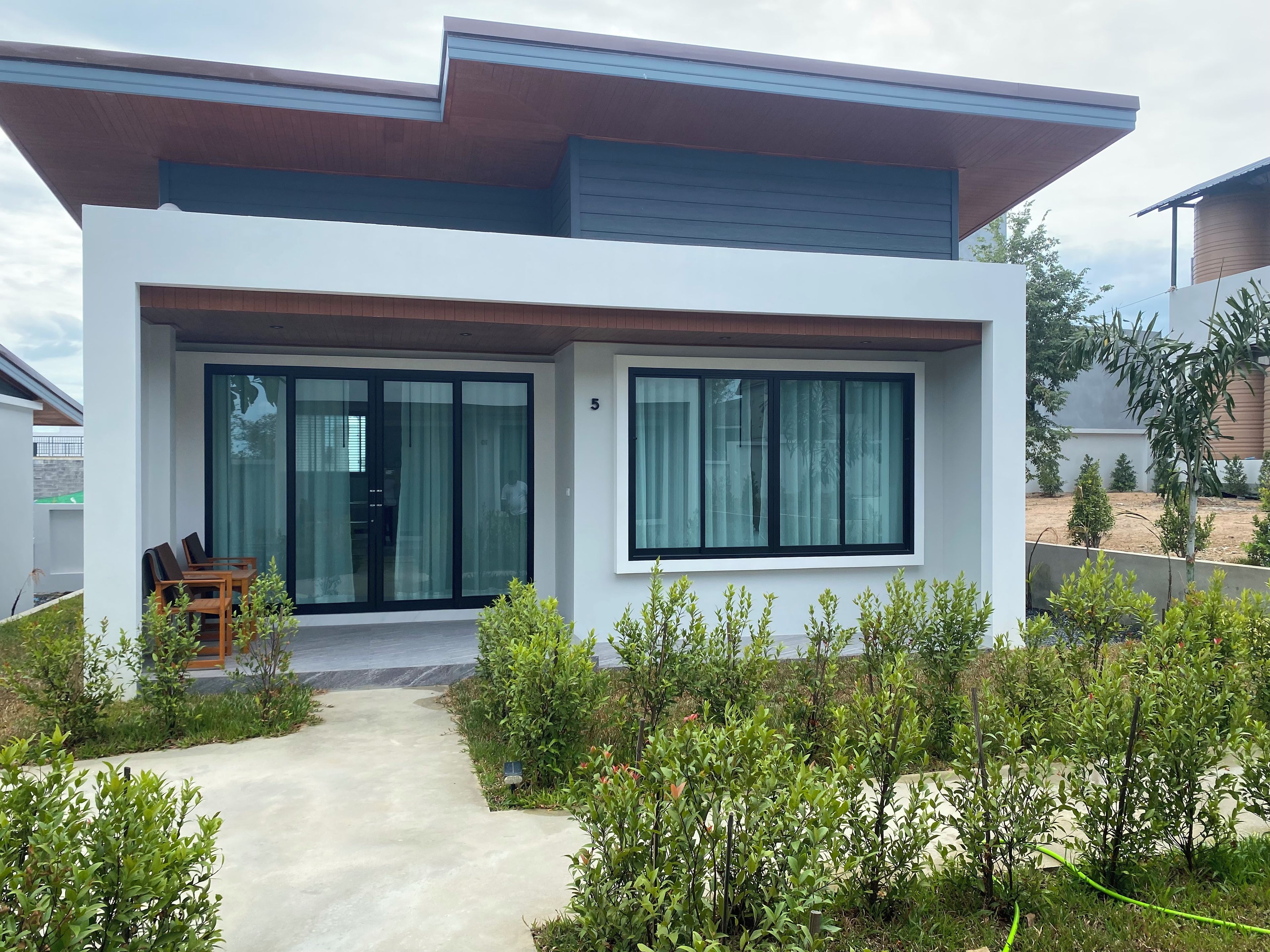 A modern two-story house with a covered patio, large windows, and a well-maintained garden.