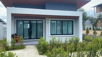 A modern two-story house with a covered patio, large windows, and a well-maintained garden.