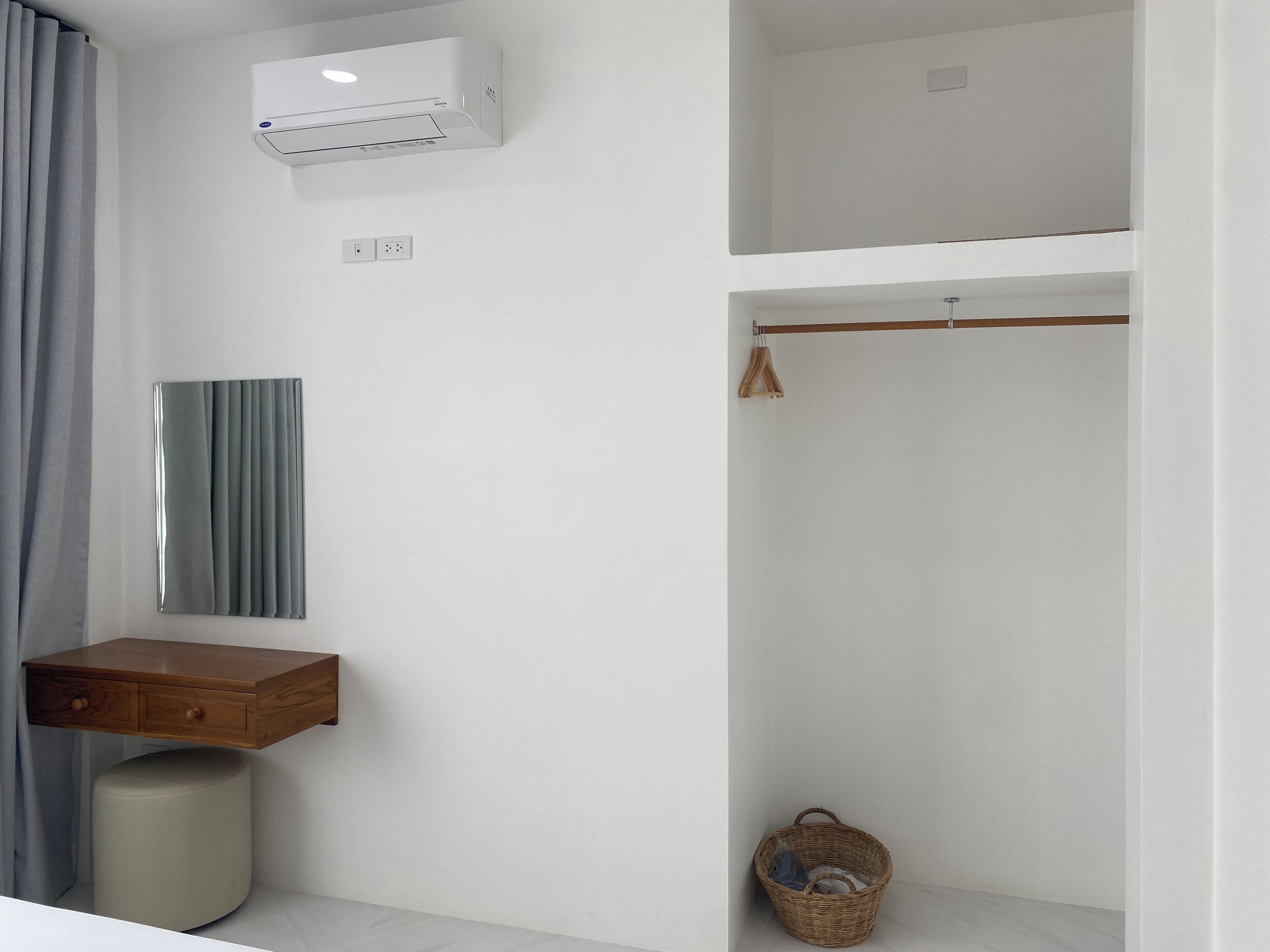 A modern bathroom with a built-in air conditioner, a mirror, a wooden vanity, and a hanging towel rack.