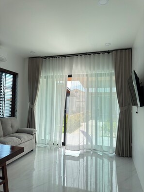 A modern living room with a sofa, a flat-screen TV, and sheer curtains. - Green Mountain View villas Koh samui (Koh samui)