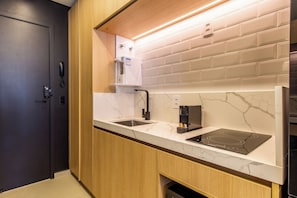 A modern kitchen with a marble countertop, a built-in sink, a coffee machine, and a black induction cooktop. - Studio Premium - 2 Blocks from NuBank Park (São Paulo)