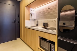 A modern kitchen with a built-in oven, microwave, and a black refrigerator. - Studio Premium - 2 Blocks from NuBank Park (São Paulo)