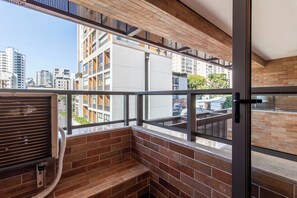 A balcony with a view of a cityscape, a window with a view of buildings, and a door with a handle. - Studio Premium - 2 Blocks from NuBank Park (São Paulo)