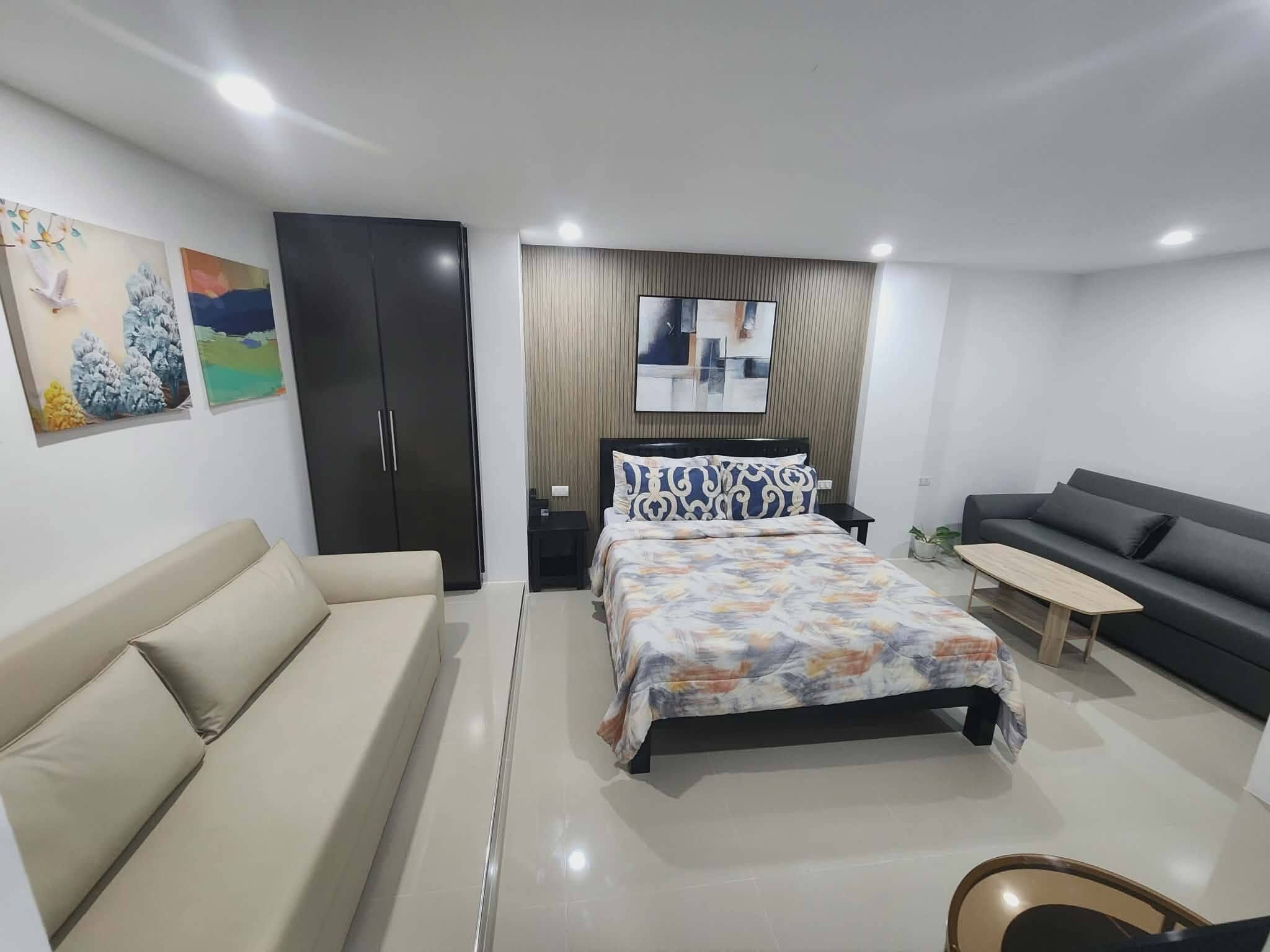 Un dormitorio moderno con cama, sofá, escritorio y armario.