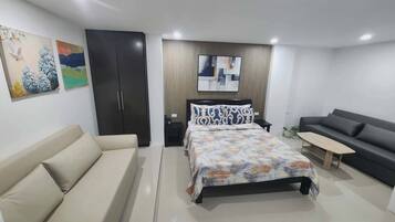 Un dormitorio moderno con cama, sofá, escritorio y armario.