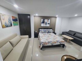 A modern bedroom with a bed, a sofa, a desk, and a wardrobe.