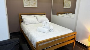 A neatly made bed with white linens and towels, a wooden headboard, and a large mirror on the wall. - Walk to Stadium and City Center (Cardiff)