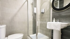 A modern bathroom with a glass-enclosed shower, a white toilet, and a sink with a towel. - Walk to Stadium and City Center (Cardiff)