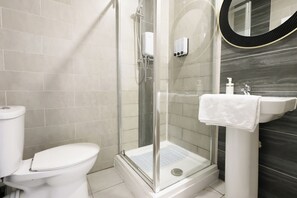 Ein modernes Badezimmer mit einer gläsernen Duschkabine, einer weißen Toilette und einem Waschbecken mit Handtuch.