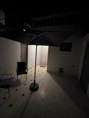 Ein schummriges Zimmer mit einer Stehlampe, einem Sessel und einem Fenster mit Vorhängen.