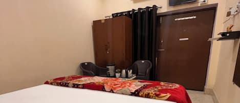 Habitación de hotel con cama, escritorio, silla, aire acondicionado, televisor y armario.