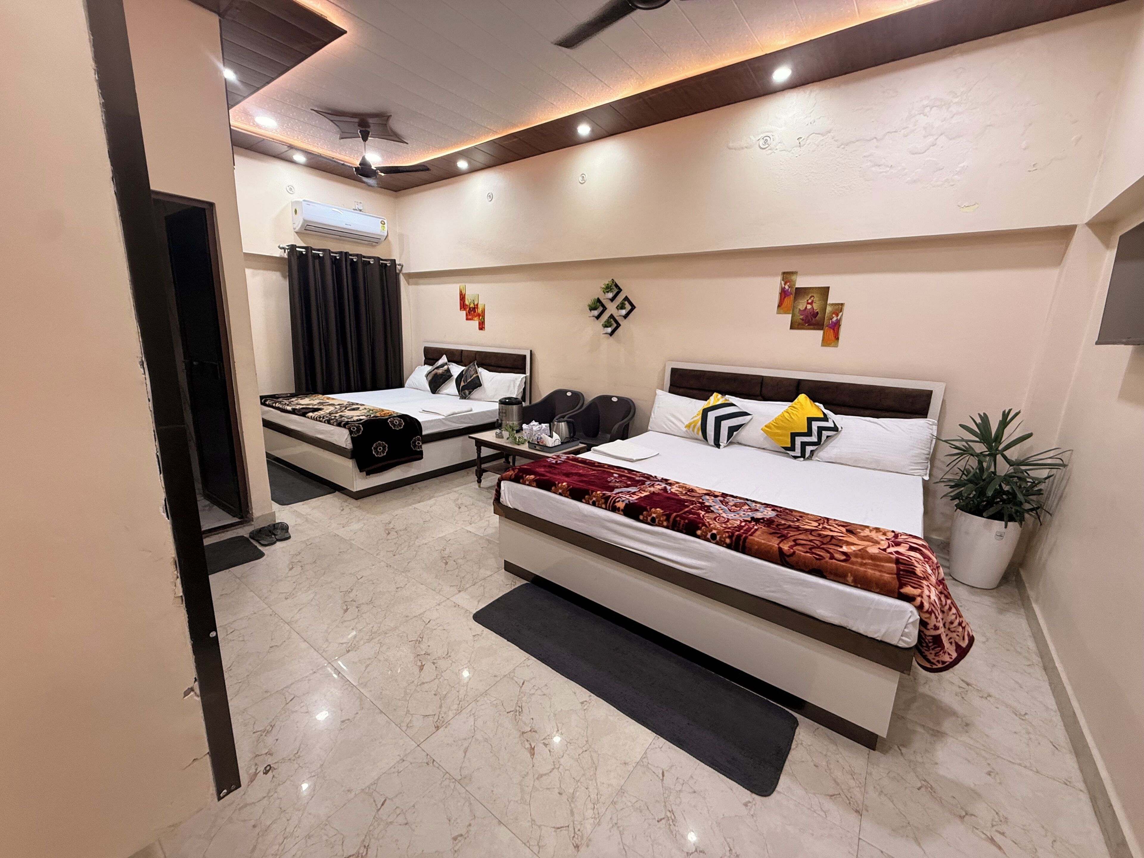 Habitación de hotel con una cama grande, mesitas de noche, ventilador de techo, aire acondicionado y una planta en maceta.