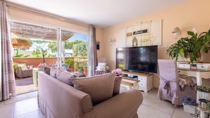 A living room with a sofa, a TV, and a dining area with a table and chairs. - Spacieux Appartement L Instant Mediterranee (Cers)
