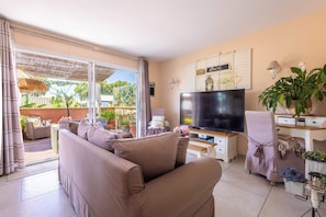 Ein Wohnzimmer mit einer Couch, einem Fernseher und einem Essbereich mit Tisch und Stühlen.