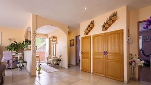A spacious hallway with a sofa, a dining area, and a wooden wardrobe with decorative items. - Spacieux Appartement L Instant Mediterranee (Cers)