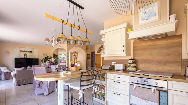 A modern kitchen with a central island, white cabinetry, and a dining area with a sofa and chairs. - Spacieux Appartement L Instant Mediterranee (Cers)