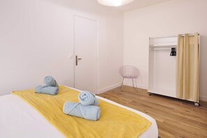 Une chambre d ’hôtel avec un lit, une armoire et une petite chaise.