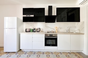 A modern kitchen with white cabinets, a black oven, a stainless steel sink, and a microwave. - Cozy flat, Halles view, AC · MyLocTravel (Béziers)