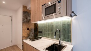 Et kompakt køkken med indbygget mikrobølgeovn, vask og en moderne backsplash.