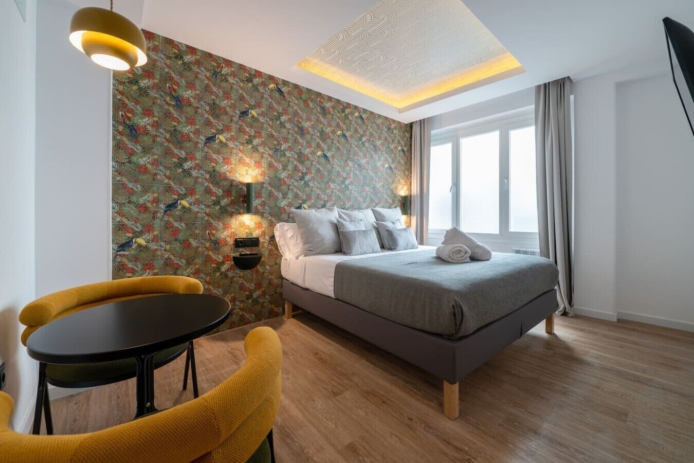 A modern bedroom with a bed, a small table, and two chairs.