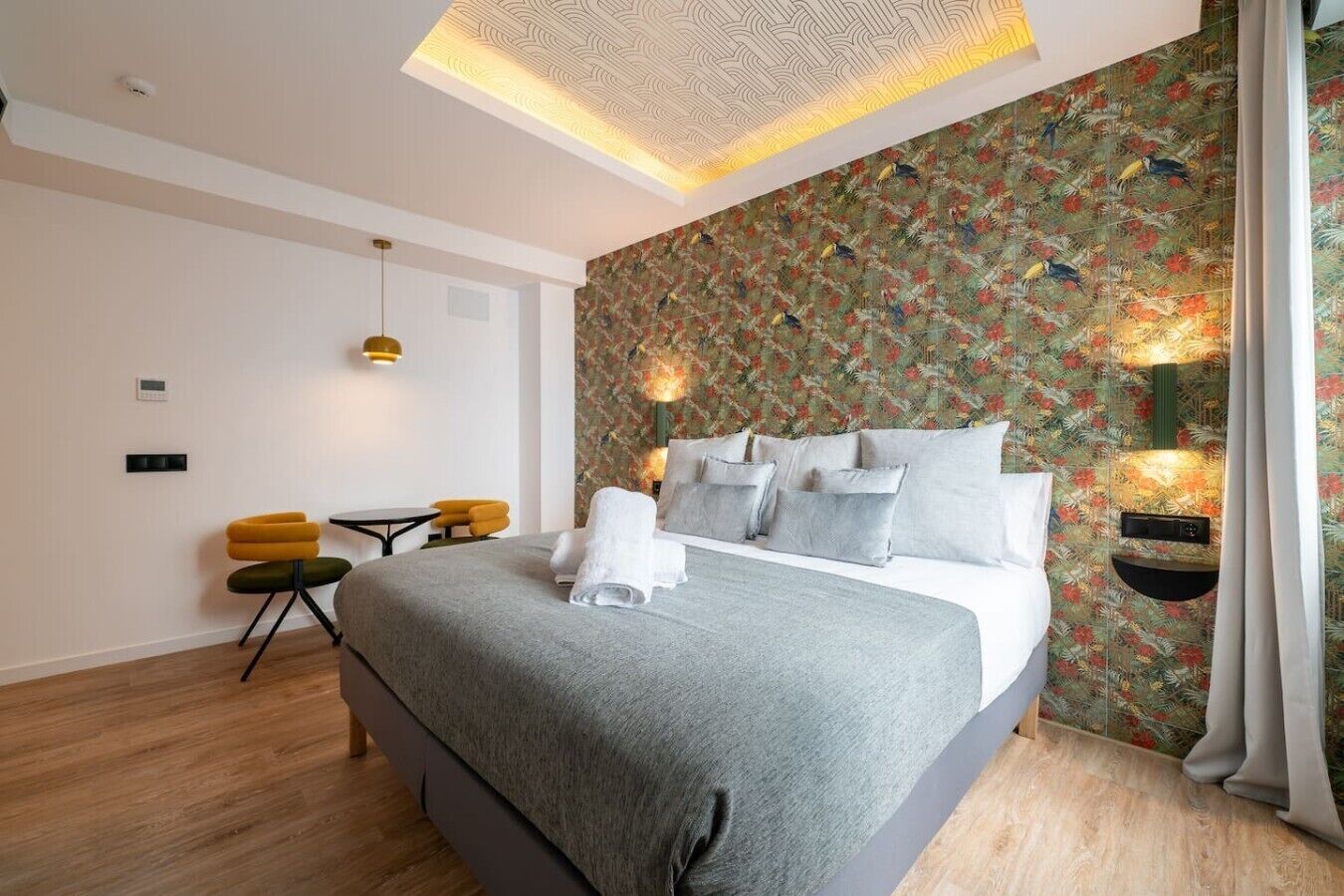 Ein modernes Hotelzimmer mit einem großen Bett, einem kleinen Schreibtisch und einem Stuhl.