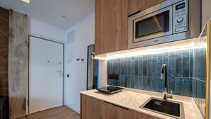 Et moderne køkken med indbygget mikroovn, en stålvask og et flisebeklædt bagpanel.