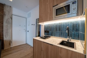 Eine moderne Küche mit eingebauter Mikrowelle, einer Edelstahl-Spüle und einer gefliesten Rückwand.