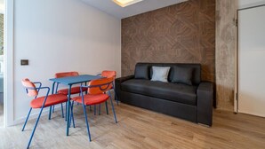 En moderne stue med sofa, stole, et bord og en væg med tapet.