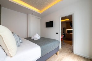 Ein modernes Schlafzimmer mit Bett, Flachbildfernseher und begehbarem Kleiderschrank.