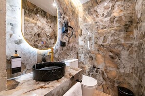 A bathroom with a marble sink, a handheld showerhead, and a toilet. - Sol Atelier | Apartments by Monaro* * * * * (Madrid)