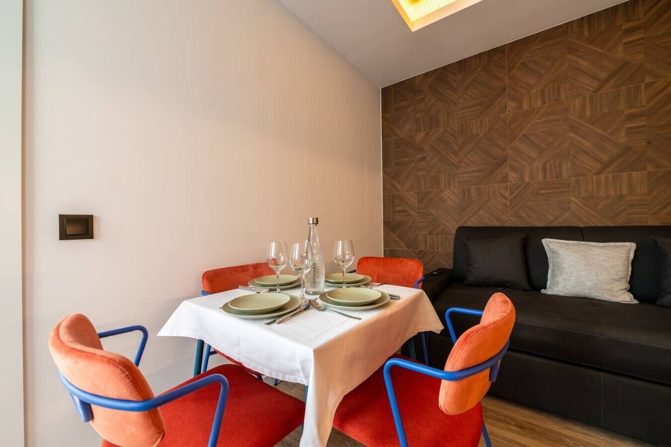 En matplats med ett bord för fyra personer, en soffa och en vägg med ett mönster.