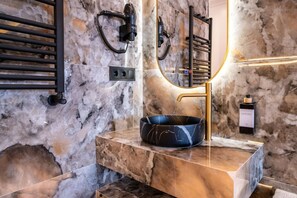 A bathroom with a marble sink, a handheld hair dryer, and a bottle of hand soap. - Sol Atelier | Apartments by Monaro* * * * * (Madrid)