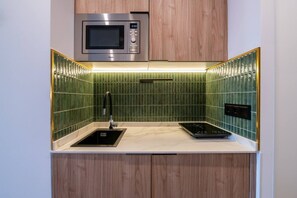 A compact kitchen with a microwave, a sink, and a stovetop. - Sol Atelier | Apartments by Monaro* * * * * (Madrid)