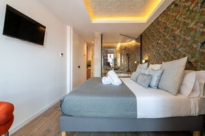 A modern hotel room with a large bed, a flat-screen TV mounted on the wall, and a decorative ceiling. - Sol Atelier | Apartments by Monaro* * * * * (Madrid)