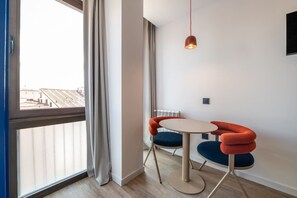 A modern room with a large window, a round table with two chairs, and a hanging light fixture. - Sol Atelier | Apartments by Monaro* * * * * (Madrid)