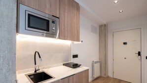 A compact kitchen with a built-in microwave, a sink, and a small countertop. - Sol Atelier | Apartments by Monaro* * * * * (Madrid)