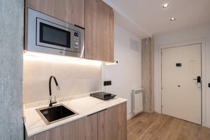 A compact kitchen with a built-in microwave, a sink, and a small countertop. - Sol Atelier | Apartments by Monaro* * * * * (Madrid)